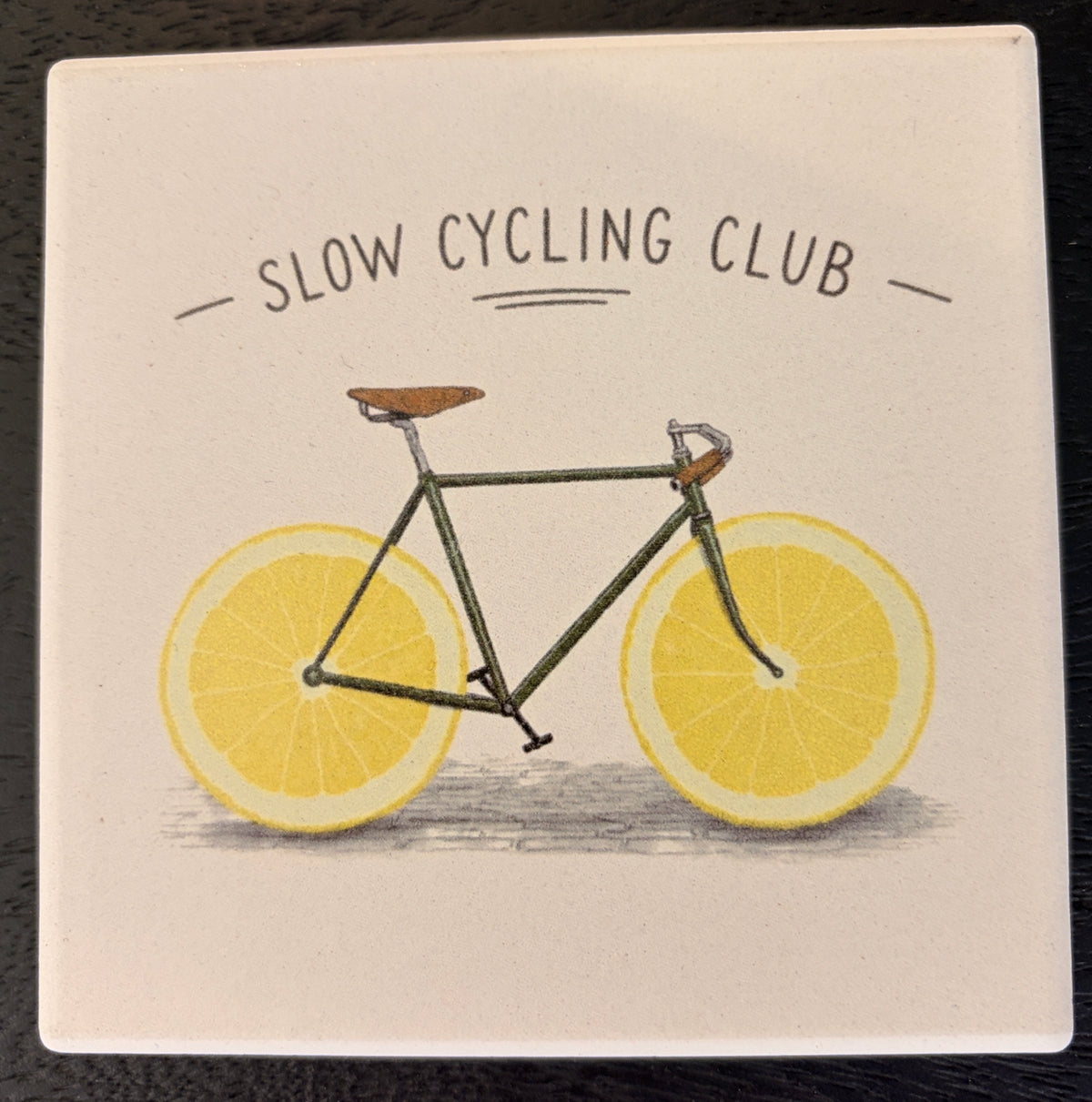 Bedruckte Fliese oder Untersetzer mit einem Vintage-Fahrrad auf Zitronenscheiben als Rädern und dem Schriftzug „Slow Cycling Club“.