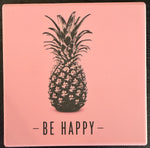 Bedruckte Fliese oder Untersetzer mit einer schwarzen Ananas auf rosafarbenem Hintergrund und dem Schriftzug „Be Happy“ im minimalistischen Design.