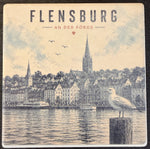Bedruckte Fliese oder Untersetzer mit einem Vintage-Panorama der Flensburger Förde, Möwe auf einem Dalben und dem Schriftzug „Flensburg an der Förde“.