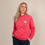 Jana trägt einen pink-roten Billybelt Pullover mit dezenter Waschung und kleinem Brustpatch vor einem neutralen Studiohintergrund.