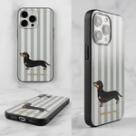 TPU Handyhülle mit schwarzem Dackel-Motiv auf salbeigrün-beigem Streifenmuster. Flexible Smartphone-Hülle mit schwarzen Seitenrändern für iPhone 14, iPhone 15 und iPhone 16. Bedruckte Dackel Handyhülle im modernen skandinavischen Design.