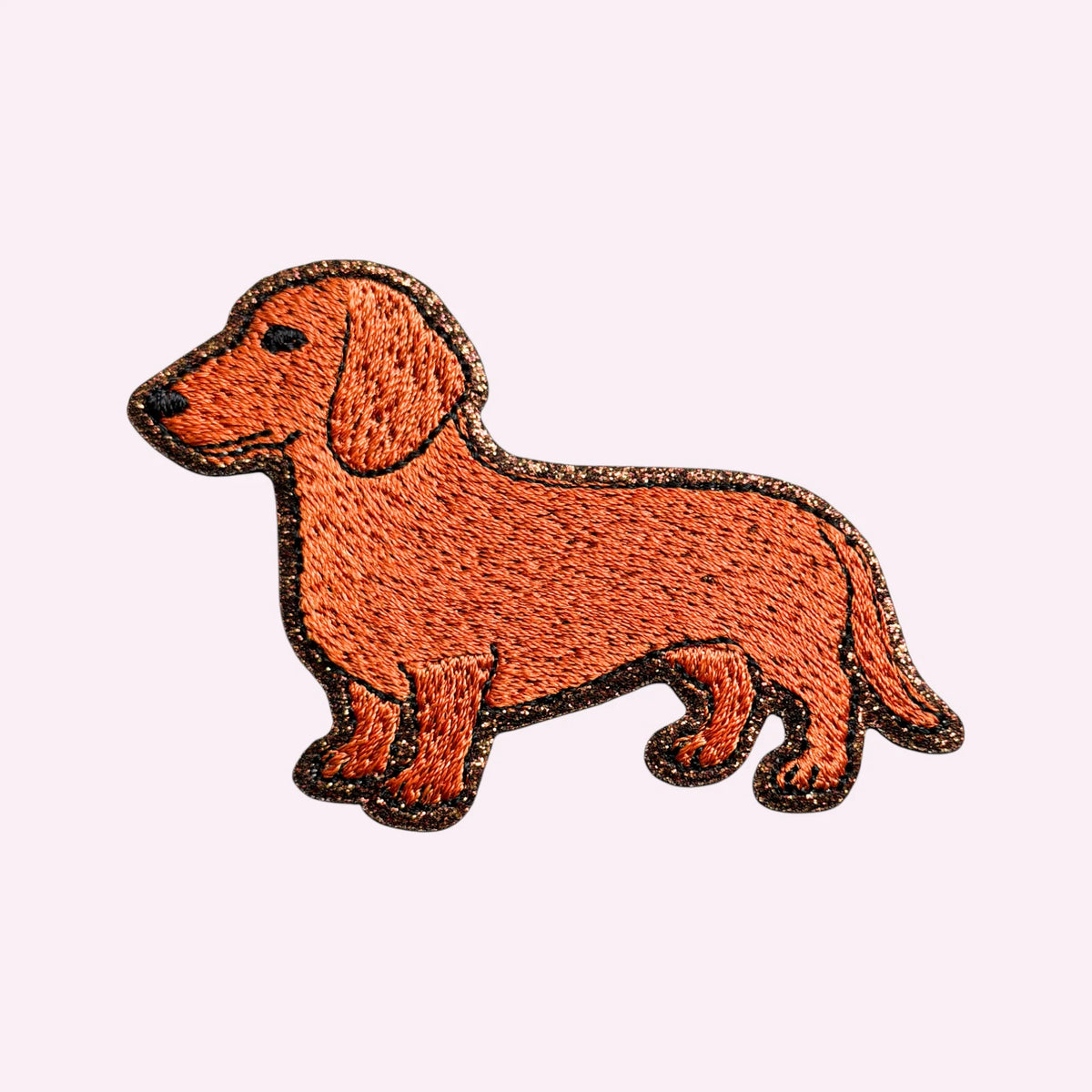 Bestickter Mimi’s Glow Motiv-Sticker mit braunem Dackel und dunkel glitzernder Umrandung.