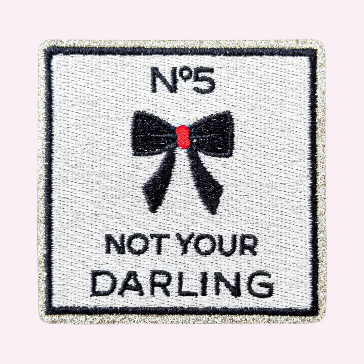 Bestickter Mimi’s Glow Motiv-Sticker „Not Your Darling“ in Weiß und Schwarz mit Schleife und goldenem Glitzerrand
