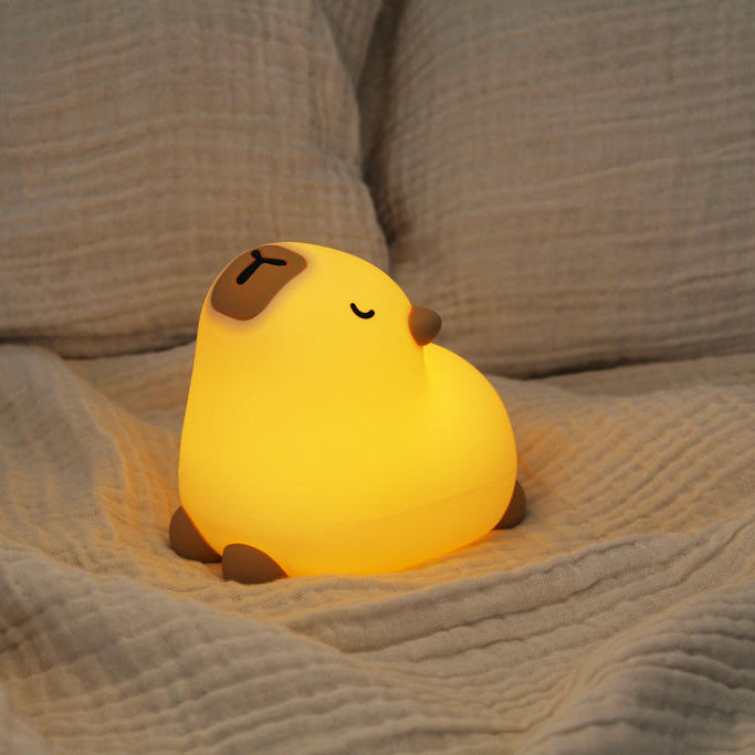 Leuchtendes Silikon-Nachtlicht Capybara Pebble auf einem beigen Sofa
