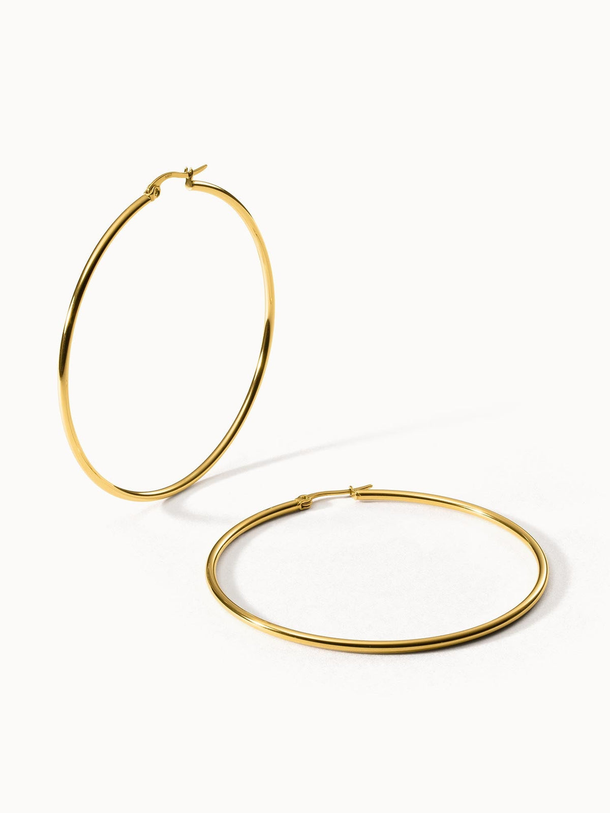 Goldene PURELEI Hoops Creolen mit 63 mm Durchmesser auf hellem Hintergrund
