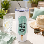 Weißer Thermobecher mit mintfarbenem Eis-am-Stiel-Motiv und „Everything is cool“-Schriftzug, transparentem Schiebedeckel und Edelstahlstrohhalm auf einem sommerlichen Terrassentisch.